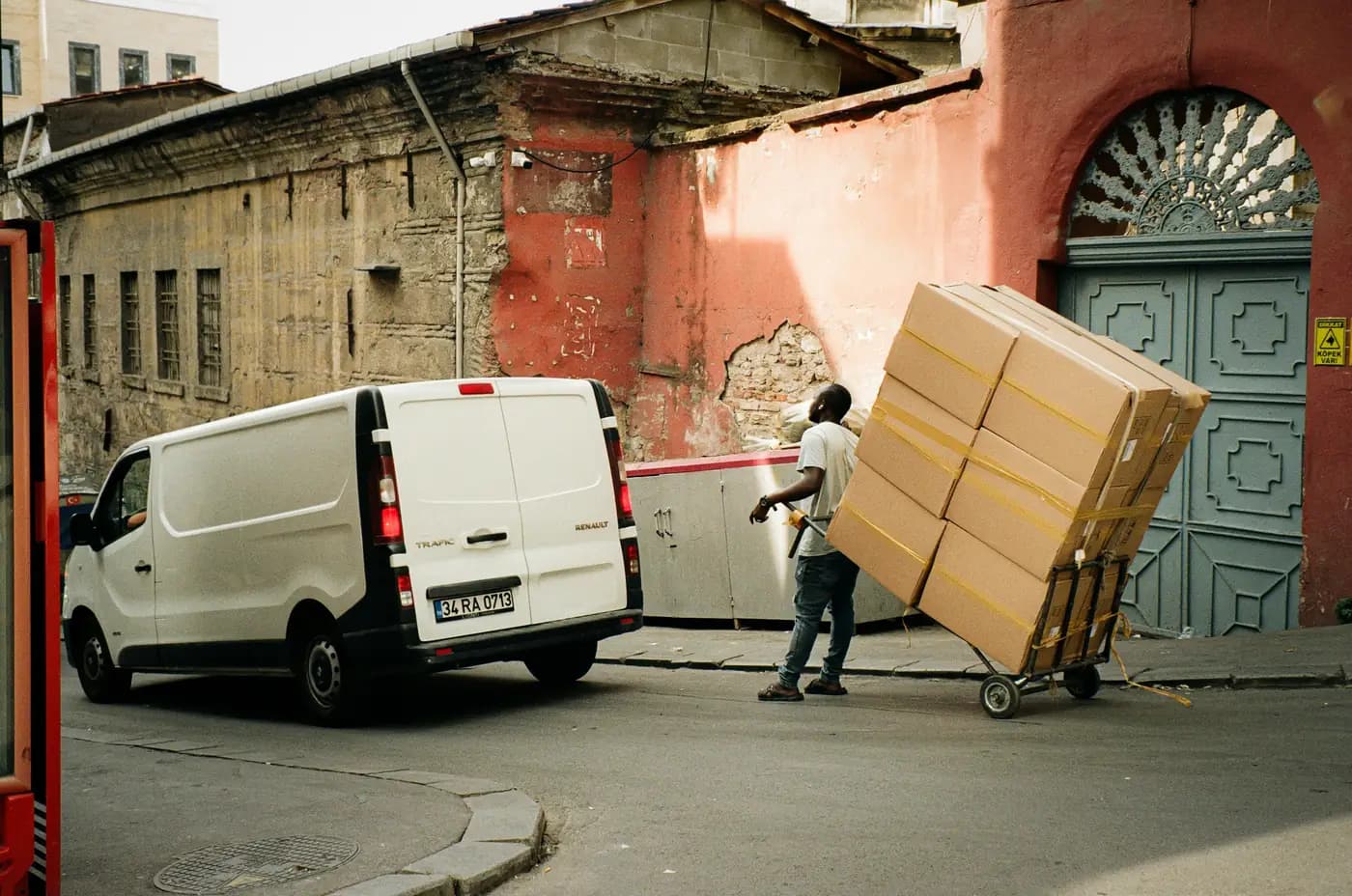 Un livreur pousse un diable chargé de cartons près de sa camionnette.